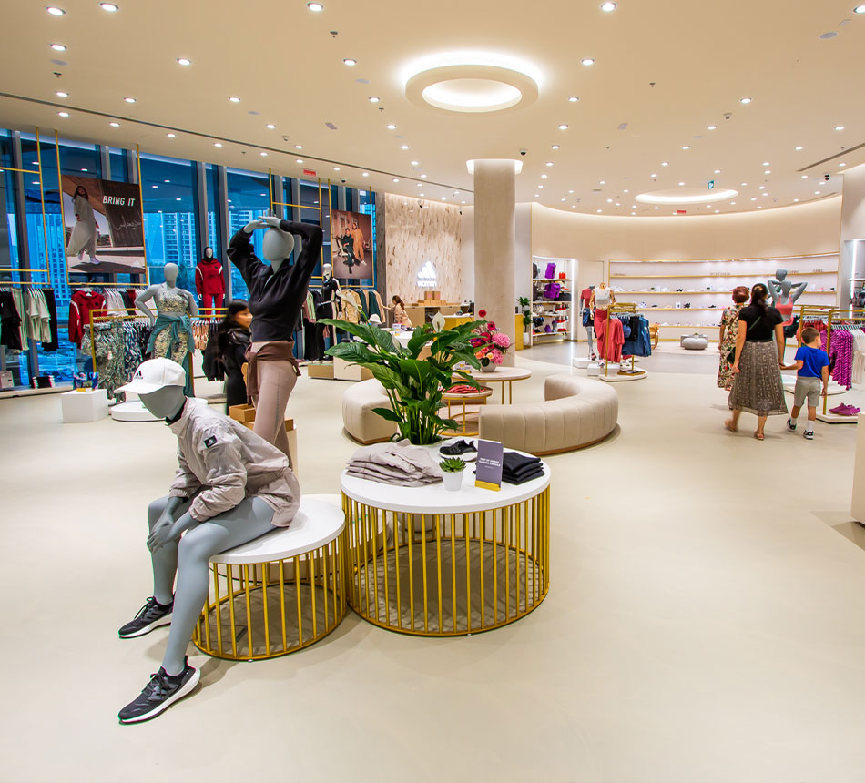 Ein adidas Store von innen, in hellen Farben, in dem Leute einkaufen (Foto)