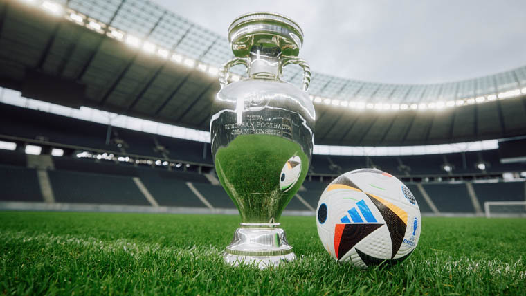 Ein Fußball der EURO 2024 und der EM-Pokal stehen in einem Stadion am Rasen (Foto)