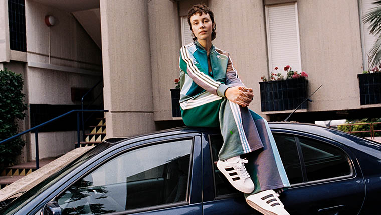 A woman wearing a green and violet adidas sweat suit also wears adidas Superstar shoes (Photo)