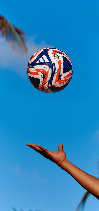 Dieses Bild zeigt eine Person mit ausgestrecktem Arm, die einen Fußball hält. Im Hintergrund ist der Himmel zu sehen, was darauf schließen lässt, dass sich die Person tagsüber im Freien befindet.