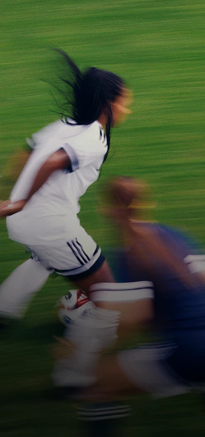 Das Bild ist ein Foto eines Fußballspielers in Aktion auf dem Feld. Der Spieler ist aufgrund der Bewegung unscharf, was darauf hindeutet, dass er während der Aufnahme rennt oder sich schnell bewegt hat.