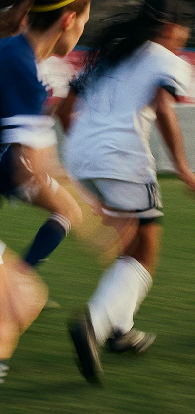 Das Bild ist ein Foto eines Fußballspielers in Aktion auf dem Feld. Der Spieler ist aufgrund der Bewegung unscharf, was darauf hindeutet, dass er während der Aufnahme rennt oder sich schnell bewegt hat.