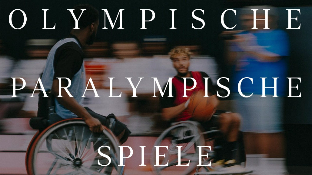 Das Bild zeigt eine Person im Rollstuhl, die an einer Veranstaltung teilnimmt, die den Anschein erweckt, als handele es sich um eine olympische Veranstaltung. Der Teilnehmer ist aktiv beteiligt und von Menschen umgeben, möglicherweise Teammitgliedern oder Mitbewerbern. Das Wasserzeichen der Paralympics und ein Text, der diesen Zusammenhang hervorhebt, sind vorhanden und weisen darauf hin, dass sich der Inhalt auf Parasportarten im Rahmen der Olympischen Spiele konzentriert.