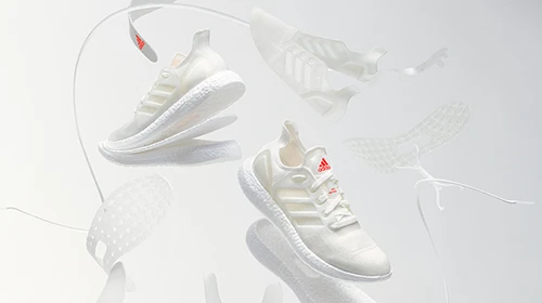 Dies ist ein Bild eines Paars weißer Adidas-Sneaker, auf dem die Teile um sie herumfließen, um zu veranschaulichen, woraus ein solcher Sneaker besteht. Es ist ein computergeneriertes Bild.