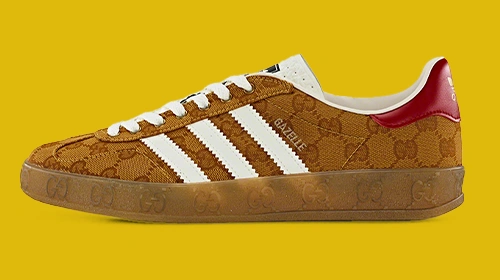 Das Bild zeigt einen Adidas-Schuh im Sneaker-Design. Der Markenname „GUCCI“ überlappt eine Seite des Schuhs, was darauf schließen lässt, dass es sich um eine Zusammenarbeit mit Gucci handeln könnte. (Foto)