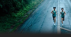 The image shows a running track with runners in motion during a rainy evening or night.