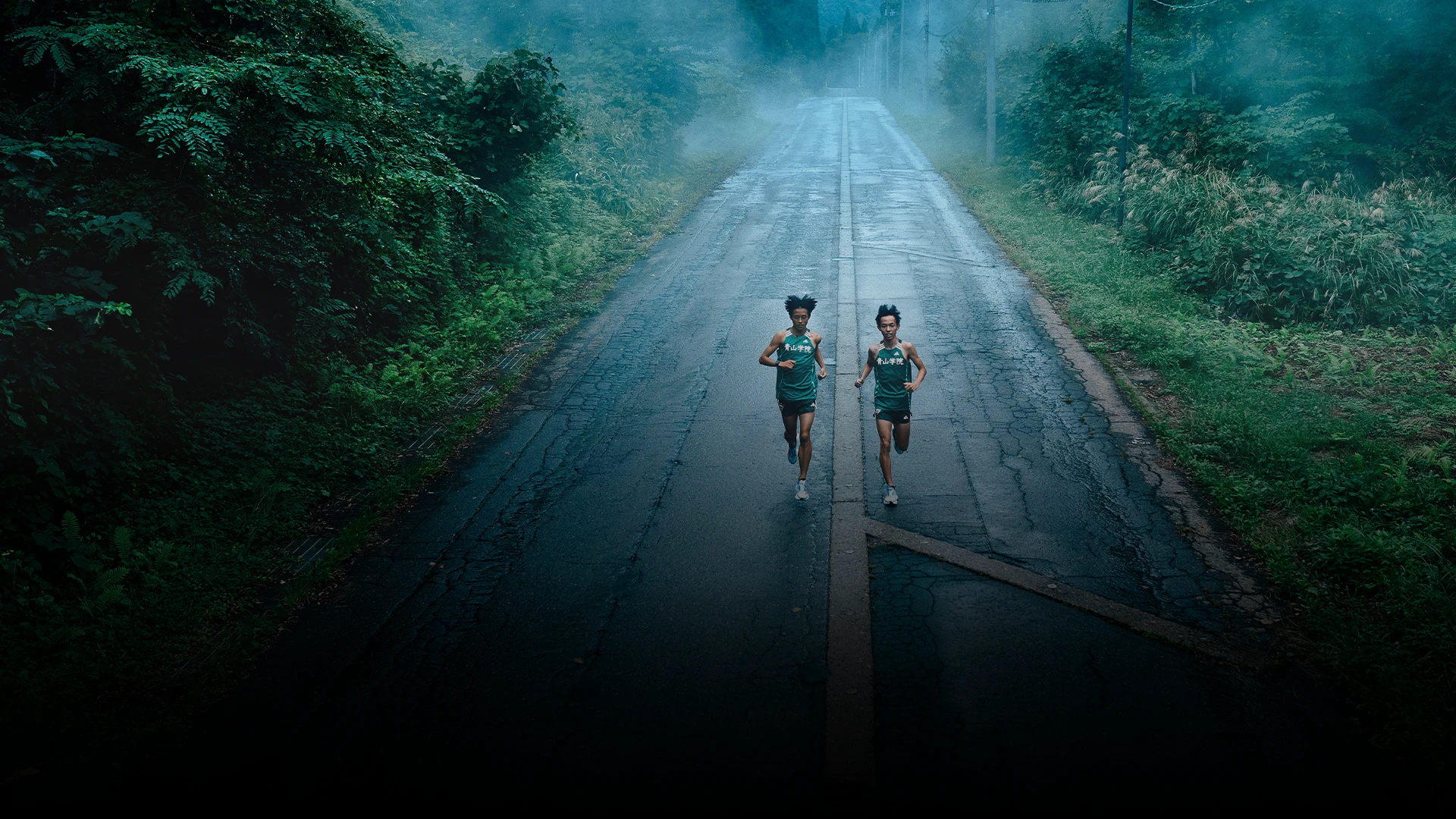 The image shows a running track with runners in motion during a rainy evening or night.