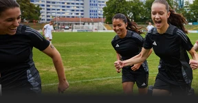 The image shows a group of female athletes. They are running on a soccer field, looking joyfully. There's a sense of camaraderie and celebration, as they all appear to be smiling and enjoying a moment together.