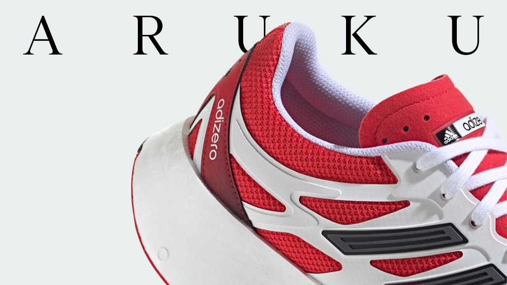 The image shows a pair of sports shoes against a white background. On the top side of the image, we can see a text "Aruku" written in capitals. Additionally, there's an upside-down adidas logo on one of the sneakers. The overall impression is that the image is likely for promotional or sales purposes.