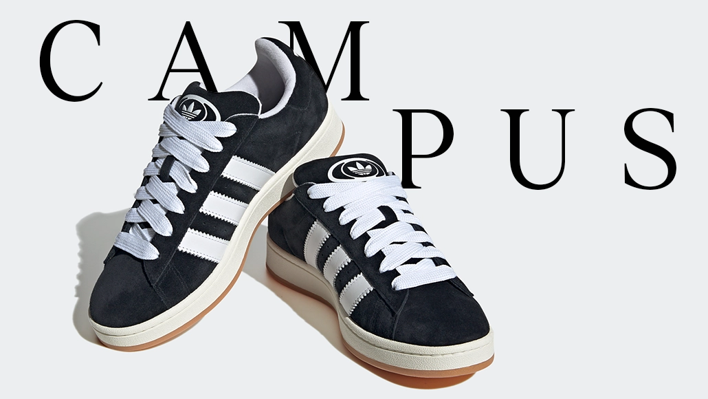 The image shows a pair of Adidas Campus sneakers displayed on a white surface with the word "CAMPUS" above. The sneakers are black with white soles and have a distinctive look featuring three stripes on each side. There is a brand logo visible at the top of them.