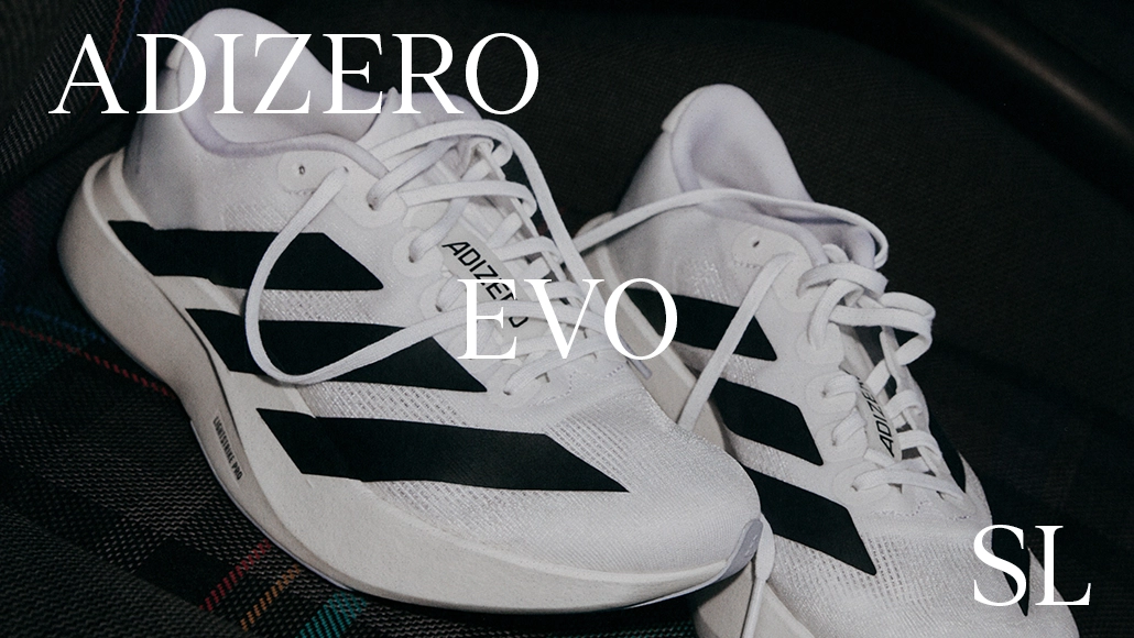 This is an image of a pair of Adizero sneakers. The shoes are predominantly white with black stripes. Overlaid on the image is text that says "ADIZERO EVO".