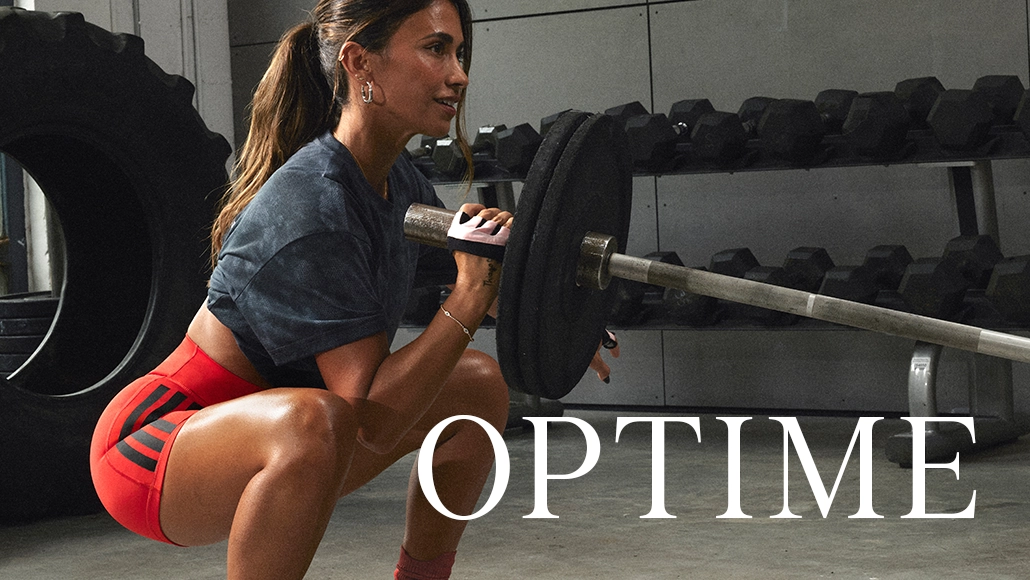 The image shows a woman exercising, with a heavy lifting barbell and weights in the background.