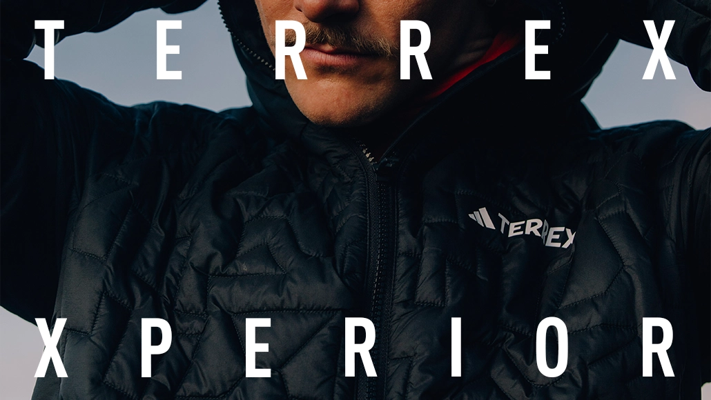 This is an advertisement for Terrex Xperior sportswear. The advertisement features a man looking up towards the camera, with his hands on his head. He appears to be in motion or possibly just relaxing and enjoying the experience of Terrex Xperior.