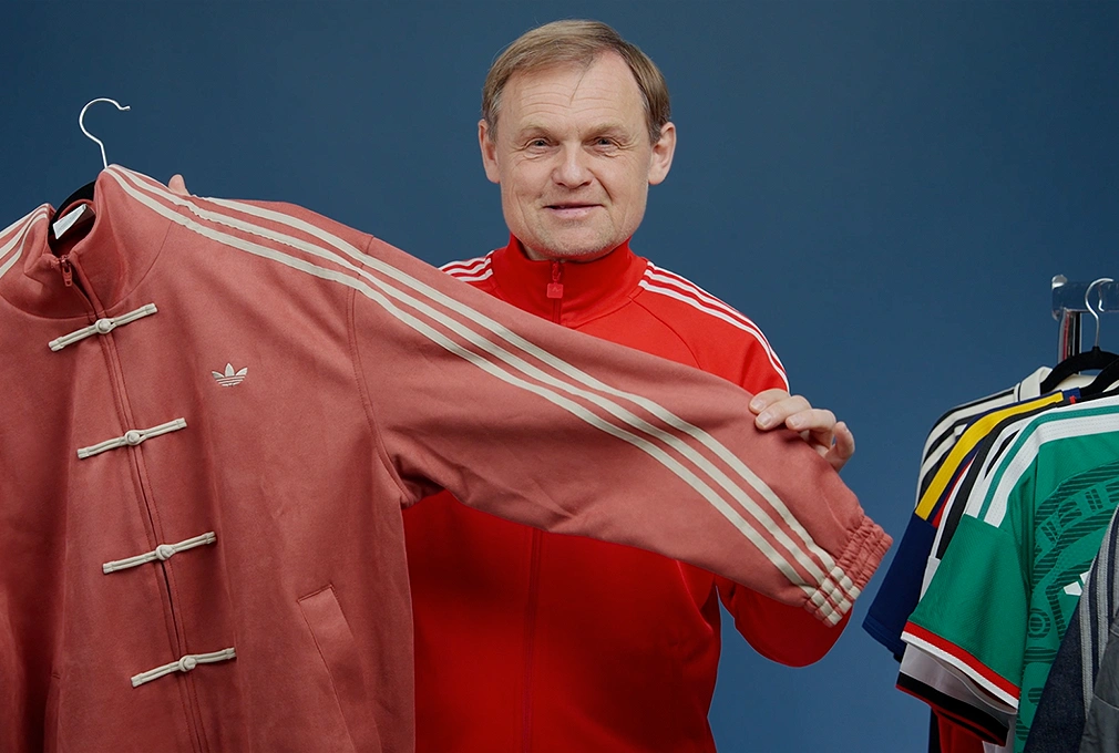 adidas CEO Bjørn Gulden presenting an adidas jacket in front of a clothing rack. (Photo)