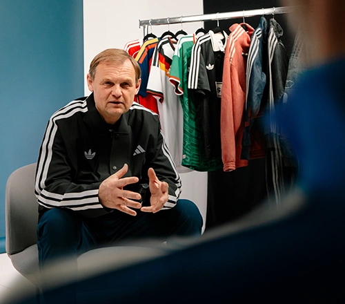 adidas CEO Bjørn Gulden in conversation in front of adidas apparel on a clothing rack. (Photo)
